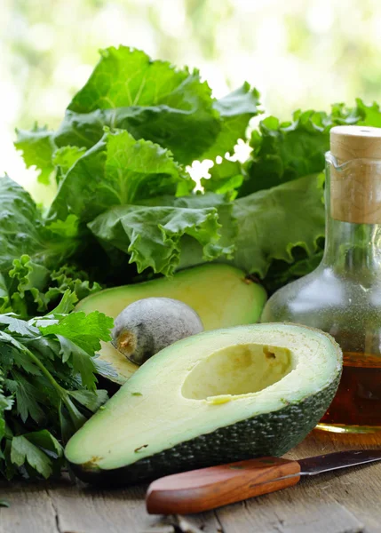 Groene rijpe avocado gesneden in de helft op een houten tafel — Stockfoto