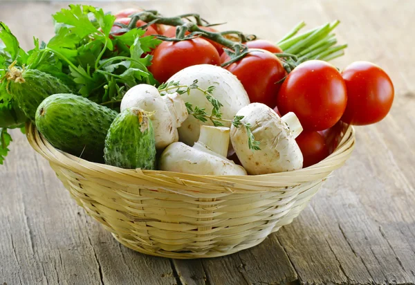 Mezclar las verduras (tomates, pepinos, setas, hierbas) en una mesa de madera — Foto de Stock