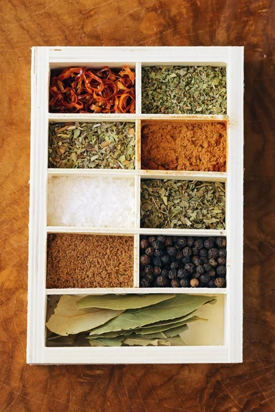 Készlet-ból különböző fűszerek (bors, só, kurkuma, babérlevél, chili, gyógynövények) egy fadobozban — Stock Fotó