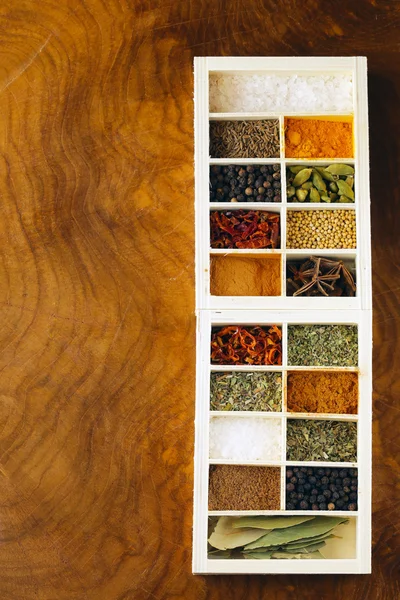 Набор различных специй (перец, соль, куркума, лавровые листья, чили, травы) в деревянной коробке — стоковое фото