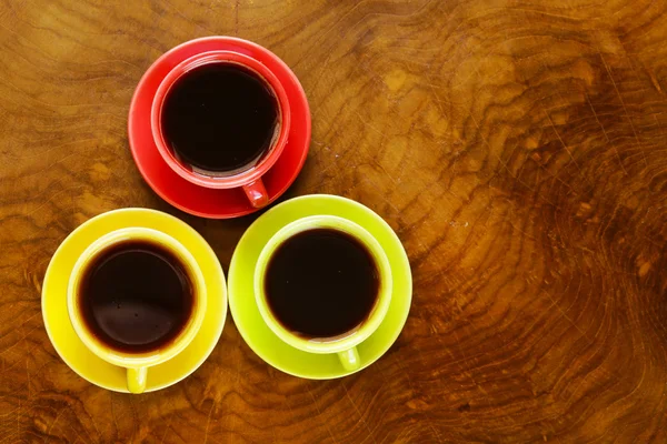 Tazze di caffè colorate su uno sfondo di legno — Foto Stock