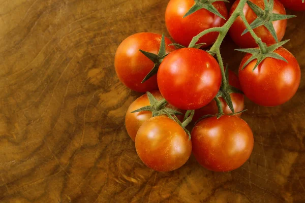 Сочные помидоры черри на ветке на деревянном фоне — стоковое фото