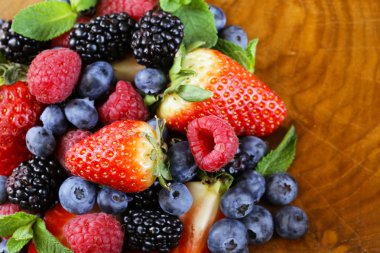 Berry çeşitler - ahududu, böğürtlen, çilek, yaban mersini ahşap arka plan üzerinde