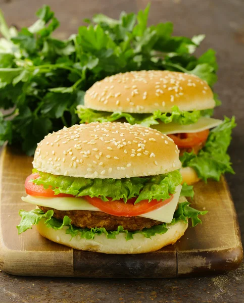 Cheeseburger tradizionale con lattuga verde e pomodori su fondo di legno — Foto Stock