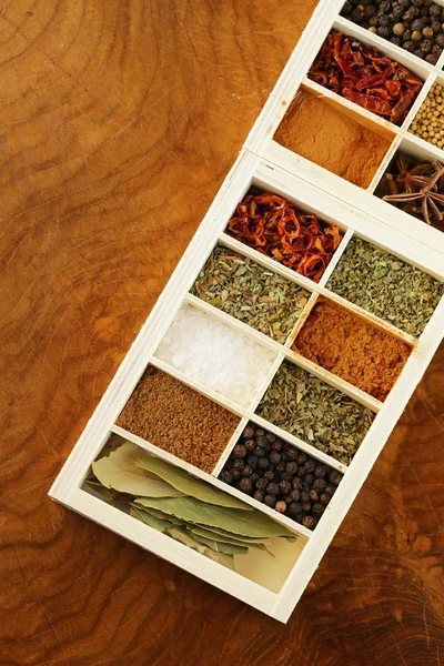 Bir ahşap kutu içinde farklı baharatlar (biber, tuz, zerdeçal, defne yaprağı, biber, otlar) kümesi — Stok fotoğraf