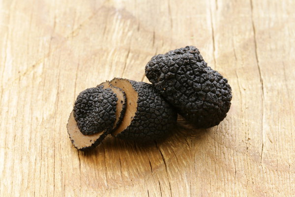 Expensive rare black truffle mushroom - gourmet vegetable on a wooden background