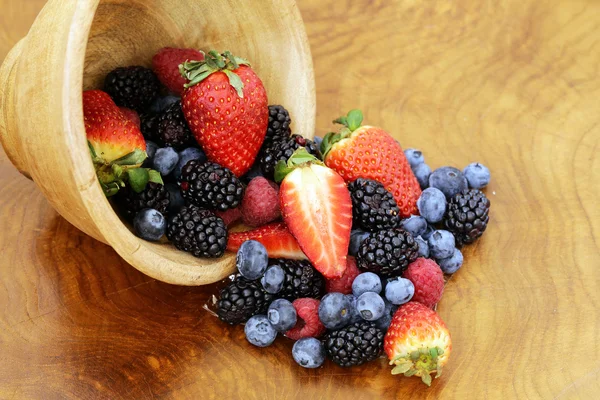 Berry sortiment - maliny, ostružiny, jahody, borůvky na dřevěné pozadí — Stock fotografie