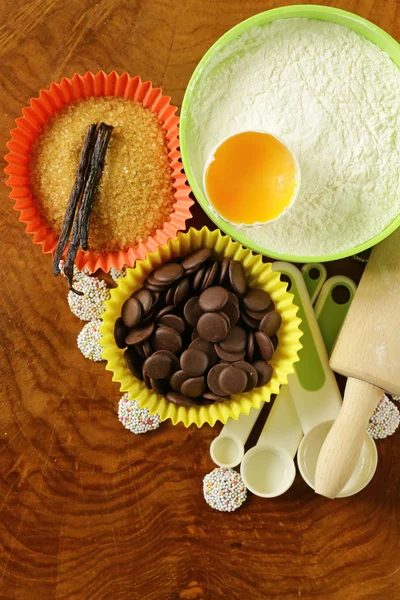Ingredientes de cozedura (açúcar, baunilha, farinha, ovo, chocolate) em uma mesa de madeira — Fotografia de Stock