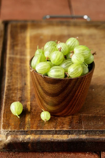 Bayas grosellas verdes en un vaso sobre la mesa — Foto de Stock