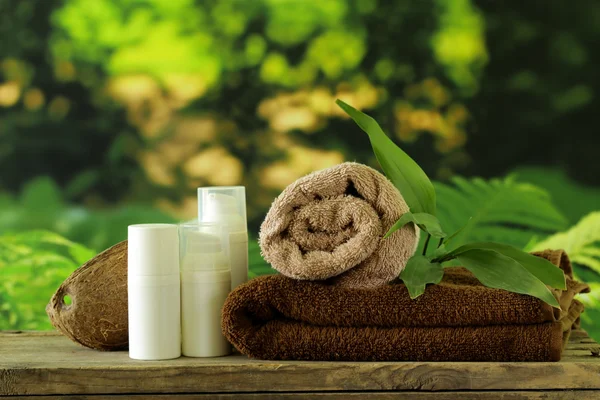 Spa koncept - ręczniki i ciała krem na naturalne tło zielony — Zdjęcie stockowe