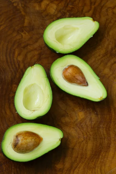 Reife Bio-Avocado halbiert auf einem hölzernen Hintergrund — Stockfoto