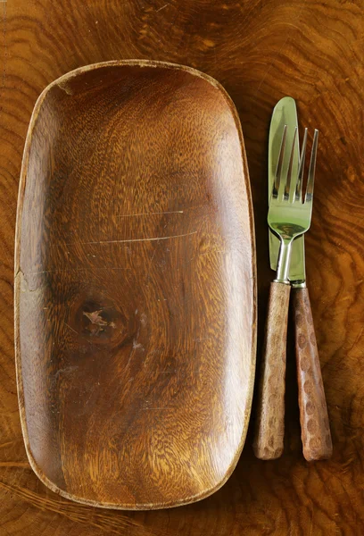 Assiette vide en bois et couverts sur un fond en bois — Photo