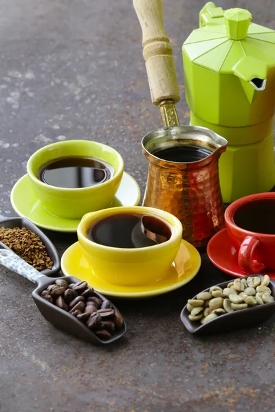 Chicchi di caffè verde, nero e diversi utensili per il caffè bollente (macinino, bollitore, cezve ) Foto Stock