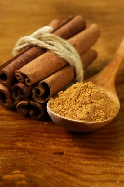 Fragrant cinnamon sticks and ground spices on a wooden background — Stock Photo, Image