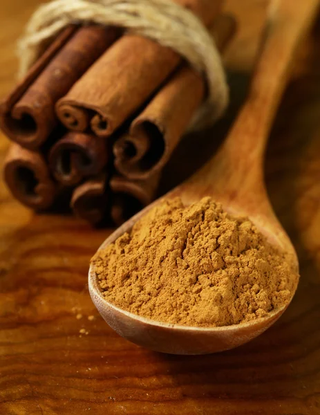 Palitos de canela fragantes y especias molidas sobre un fondo de madera —  Fotos de Stock