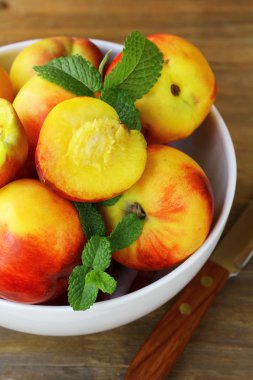 ahşap bir masa üzerine nane yaprakları ile olgun organik şeftali