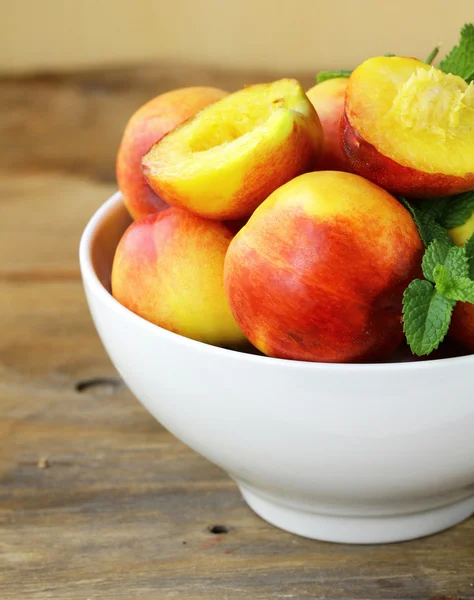 Ripe organic peaches with mint leaves on a wooden table — Stock Photo, Image