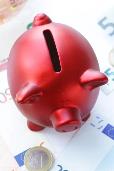 red piggy bank with euro banknotes and coins