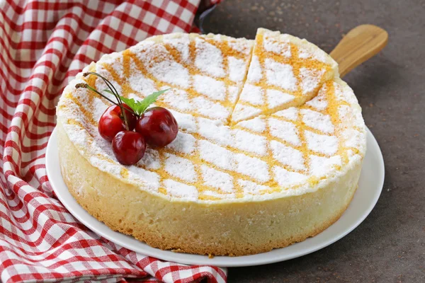 Homemade cheesecake with powdered sugar and cherry on a white plate — Stock Photo, Image