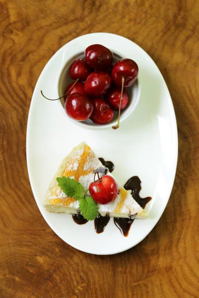 Cheesecake caseiro com açúcar em pó e cereja em um prato branco — Fotografia de Stock