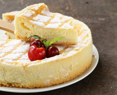 pudra şekeri ve beyaz tabakta kiraz ile ev yapımı cheesecake