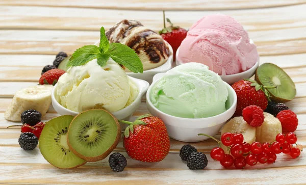 Verschiedene Eissorten Erdbeere, Banane, Minze, Schokolade und frische Beeren auf dem Holztisch — Stockfoto