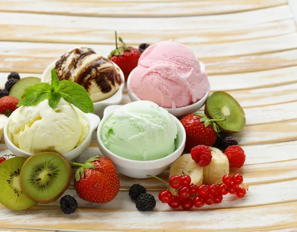 Verschiedene Eissorten Erdbeere, Banane, Minze, Schokolade und frische Beeren auf dem Holztisch — Stockfoto