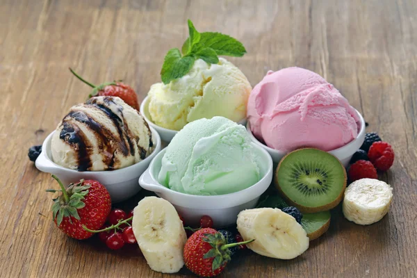 Verschiedene Eissorten Erdbeere, Banane, Minze, Schokolade und frische Beeren auf dem Holztisch — Stockfoto