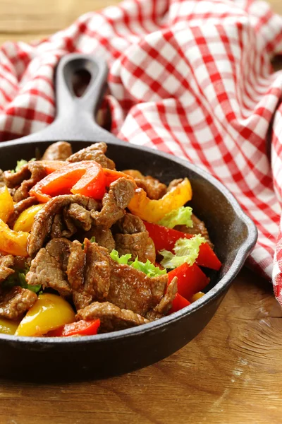 Rindfleisch-Fajitas mit bunten Paprika in der Pfanne auf einem Holztisch — Stockfoto