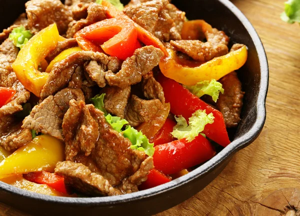 Beef fajitas med färgglada paprika i pannan på ett träbord — Stockfoto