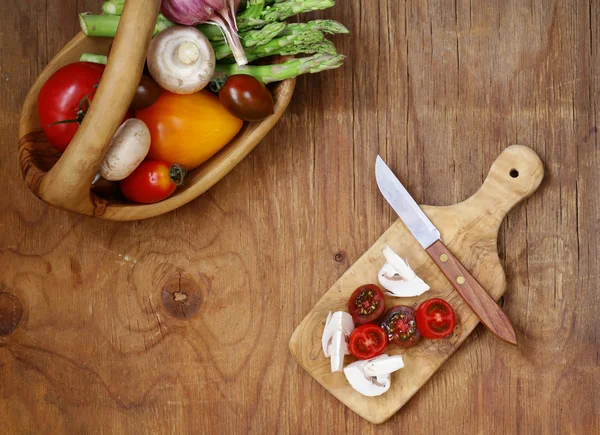 Espárragos, tomates, ajo, champiñones en una canasta sobre un fondo de madera — Foto de Stock