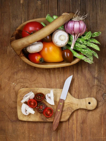 Espárragos, tomates, ajo, champiñones en una canasta sobre un fondo de madera — Foto de Stock