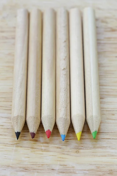 Diverse matite di legno colorate su uno sfondo di legno — Foto Stock