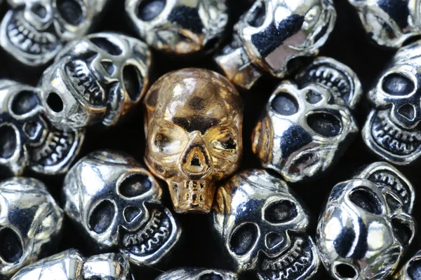 Gold unique skull among ordinary metal skulls — Stock Photo, Image