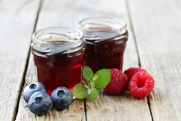 Blueberry and raspberry jam in a glass jar on a wooden table, rustic style — Stock Photo, Image