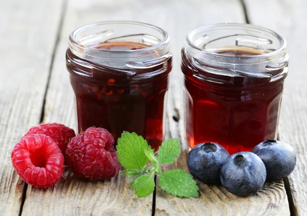 Blueberry and raspberry jam in a glass jar on a wooden table, rustic style — Stock Photo, Image