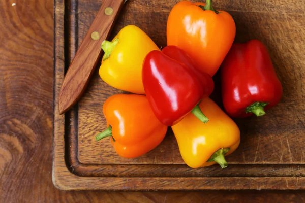 Fresh organic bell peppers on a wooden board — Stock Photo, Image