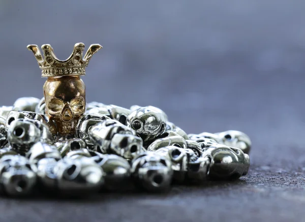 Gold unique skull among ordinary metal skulls — Stock Photo, Image