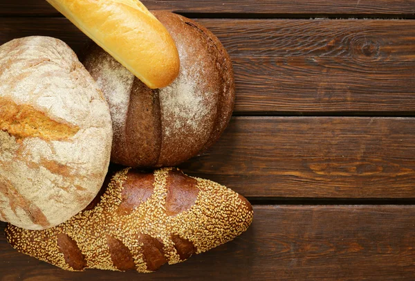 Hausgemachtes frisches Brot (Roggen, Sesam, Weiß) auf Holzgrund — Stockfoto