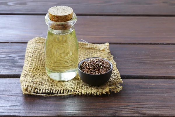 Олія насіння льону в скляних пляшках на дерев'яному столі — стокове фото