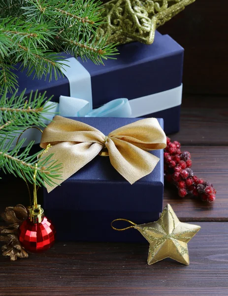 Cajas de regalo con cintas festivas y decoraciones navideñas sobre fondo de madera — Foto de Stock