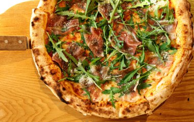 Jambonlu pizza, taze roka ve parmesan peyniri.