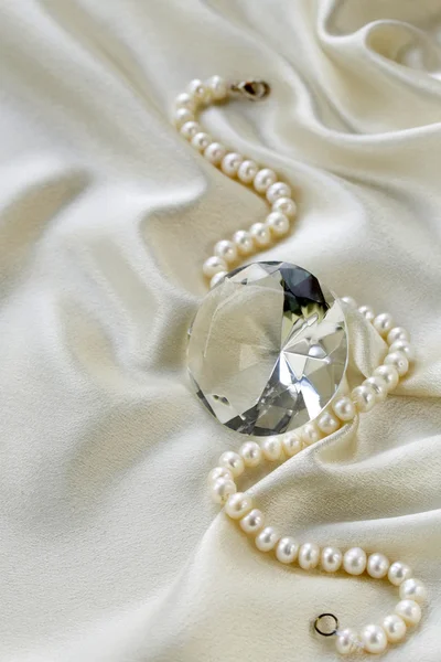 Grande diamante di vetro e collana di perle su uno sfondo di seta morbida — Foto Stock