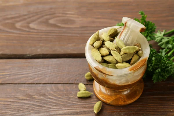 Cardamomo em um morteiro de pedra em uma mesa de madeira — Fotografia de Stock