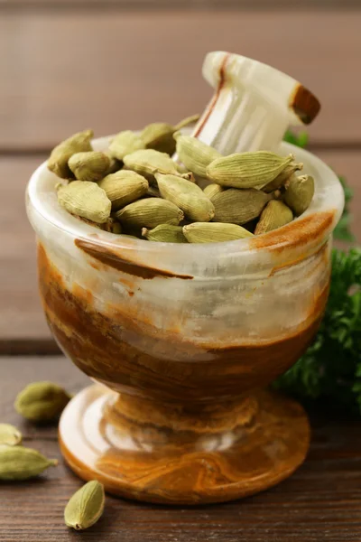 Cardamom  in a stone mortar on a wooden table — Stock Photo, Image