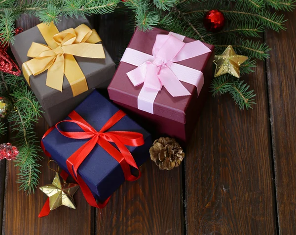 Geschenkschachteln mit festlichen Bändern und Weihnachtsdekoration auf Holzgrund — Stockfoto