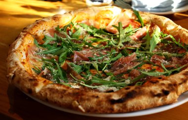 Jambonlu pizza, taze roka ve parmesan peyniri.