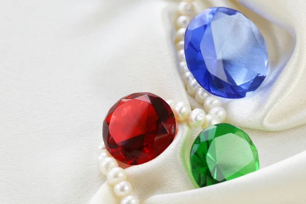 Diamantes de vidro coloridos em um fundo de seda macia — Fotografia de Stock