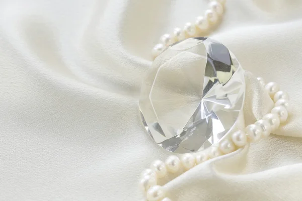 Grande diamante de vidro e colar de pérolas em um fundo de seda macia — Fotografia de Stock