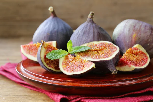 Свежие органические фиолетовые фрукты на деревянной тарелке — стоковое фото